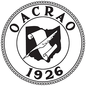 Circle with a simplified quill and paper in the middle and the text "OACRAO, 1926" around the circle's border