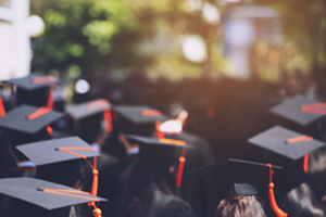 Group of graduates wearing black caps with red tassels. 