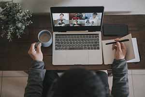 Aerial view of a figure sitting at a desk while on a video conference call.