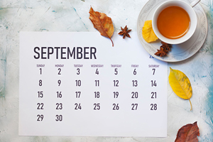 calendar of the month of September with a cup of tea and some autumn leaves off to the side