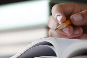 Photograph of an individual holding a pencil above a blank page.