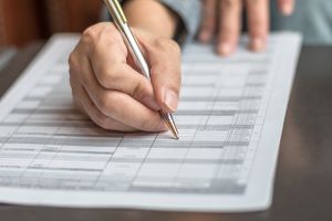 person filling out a form with a stainless steel pen