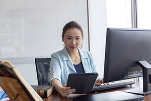 Young professional working at a desk using a computer and tablet.