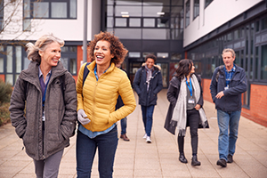 Group of adult students walking away from a building.