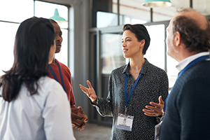 businesswomen speaking to a group of professionals 