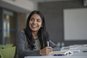 Young woman smiling and studying with open book.