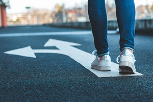 two feet walking on sidewalk with arrows pointing in different directions