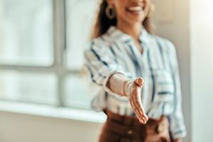 Photograph of an individual with their arm extended for a handshake.