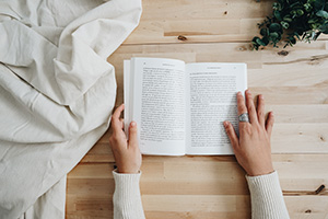 person reading a book on a butcher block surface 