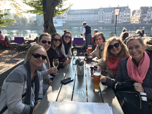  Danielle McMartin, Inga Wheeler, Katrina Brown, Joanna McCord, Neringa Tuyilingire, Kristy Sauerbry, Jenifer Ruby smile for a photo at an outdoor restaurant