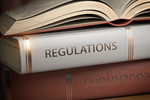 Stack of regulatory books on a table with one open on top.