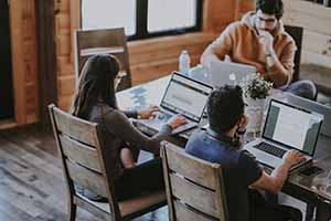 3 people working on laptops at a table.