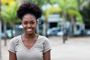 female of color wearing a beige t-shirt while smiling at the camera