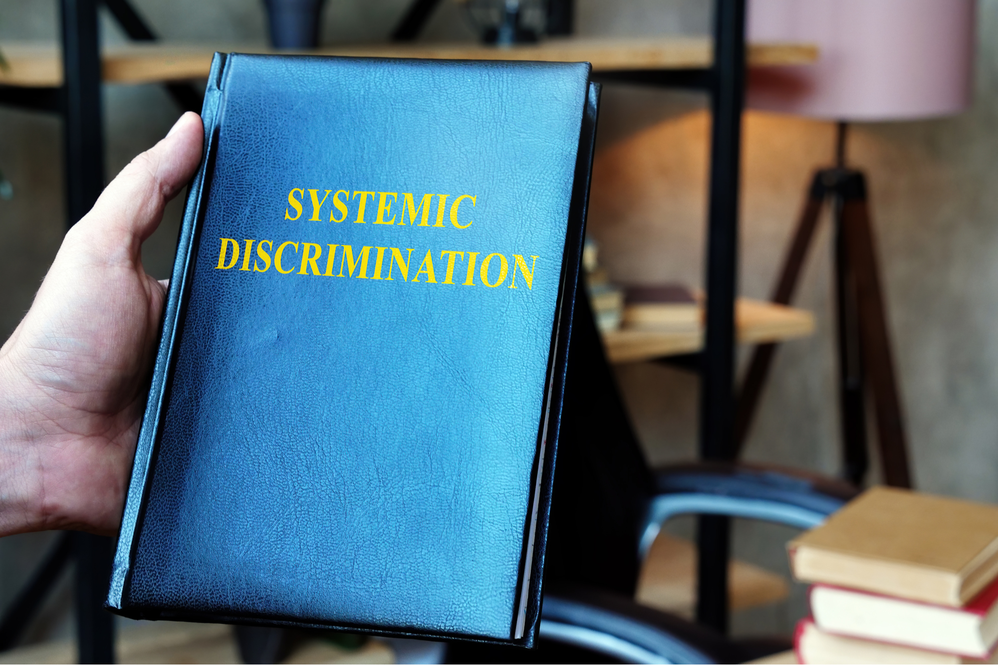 black leather bound book titled "systemic discrimination"