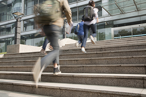 Students walking up stairs towards a campus.