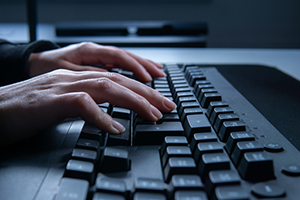 Photograph of an individual typing on a keyboard.