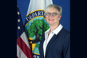 Diane Jones standing in front of a Department of Education flag and a Stars & Stripes