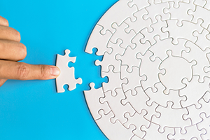 hand placing the final piece of a blank circular puzzle 