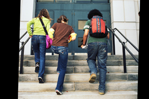 three school children walk up the steps of a building