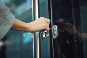 hand use keys to unlock a glass door