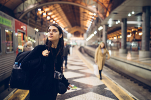 Female wearing a backpack looks over her shoulder while standing on a train platform