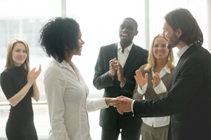 group claps and smiles for a female who is shaking hands with a male