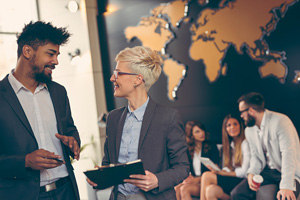 two people discuss business while three others socialize in the background