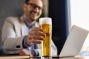 man in business suit at computer with pilsner
