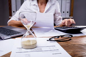 person works at their desk with an hourglass prominently displayed