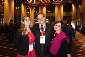 Three people dressed in formal wear pose for a photo