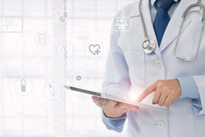 doctor in white lab coat with a stethoscope around their neck points at a tablet