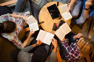 group of people engage in a book Club while sitting around a round coffee table 