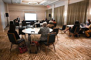 even hall with audience members sitting at circular tables while facing the front of the room