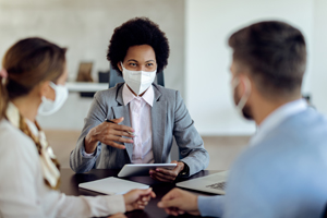 three people in a business meeting wearing face masks