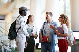 4 diverse students stand in a group and talk