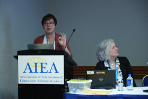 female presenting from a podium with the text "AIEA: Association of International Education Administrators" visible