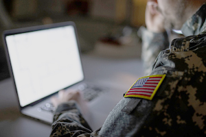 student in military uniform works on their laptop