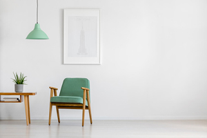 simple green chair and light fixture next to a small wooden table all situated in a blank room