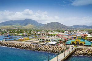 photo of a coastal community with bright buildings near the beach and a mountain off in the distance