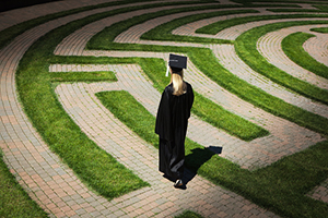 Graduate walking along a maze pathway.