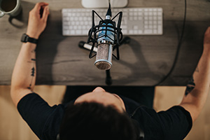 person recording themself with a mic while sitting at a wooden desk