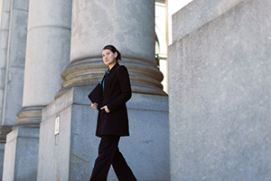 Photograph of a young woman walking down stairs away from a government building.
