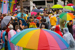 Gathering of people for pride month with rainbow umbrellas.