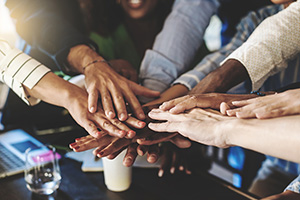 Photograph of a group of individuals holding their hands over each other.