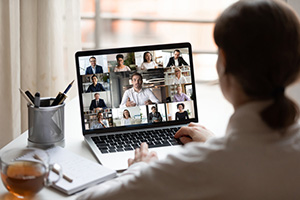 Individual attending a webinar on a laptop drinking tea.