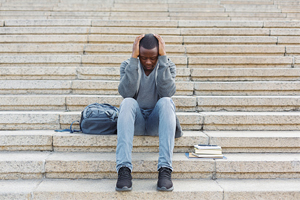 worried student on steps with head in hands