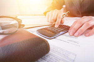 Individual working on paperwork and a calculator.