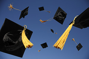 Photograph of graduation caps in the air.