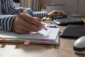 Editor working at a computer using a red highlighter.