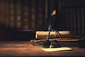 Old fashioned writing desk with quill and parchment.